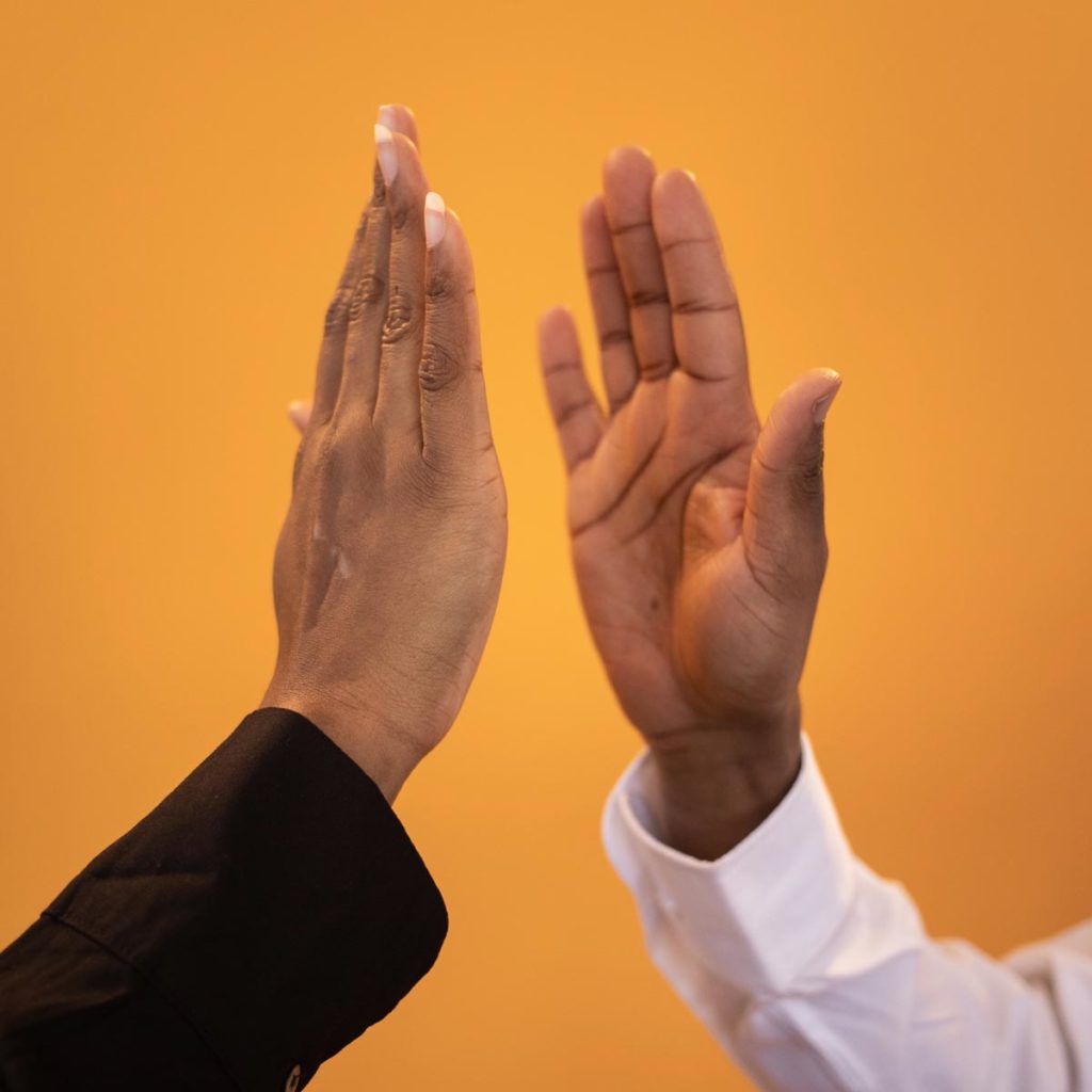 Photo of two hands high fiving, business partner coaching